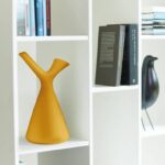 White cubby bookshelf with an orange sculptural vase and books arranged on the shelves.