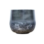 Weathered metal bowl with a rounded bottom and dark patina.