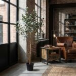 Tall potted eucalyptus plant beside a brick wall in an industrial living room with a leather armchair and wooden side table.