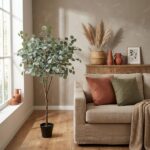 Cozy living room corner with a tall potted eucalyptus tree beside a beige sofa and earthy cushions.