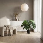 Cozy minimalist living room with a beige armchair, plaid blanket, white cabinet, round pendant lamp, and a potted monstera plant.