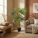 Tall potted indoor palm placed beside a beige wall in a cozy living room with a brown sofa and woven rug.