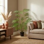 Tall potted palm plant in a living room next to a beige sofa and wooden console with ceramic vases by a sunny window