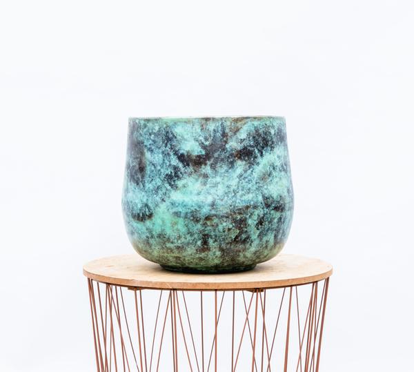 Turquoise glazed ceramic pot with green and black marbling on a wooden round stand. Intended as a decorative planter or accent piece.