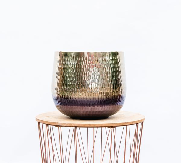 Textured, multicolored glass vase with a gradient from green to purple sits on a round wooden pedestal atop a copper-wire table (interior decor).