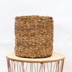 Woven basket resting on a round wooden table with a metal wire base, neutral background