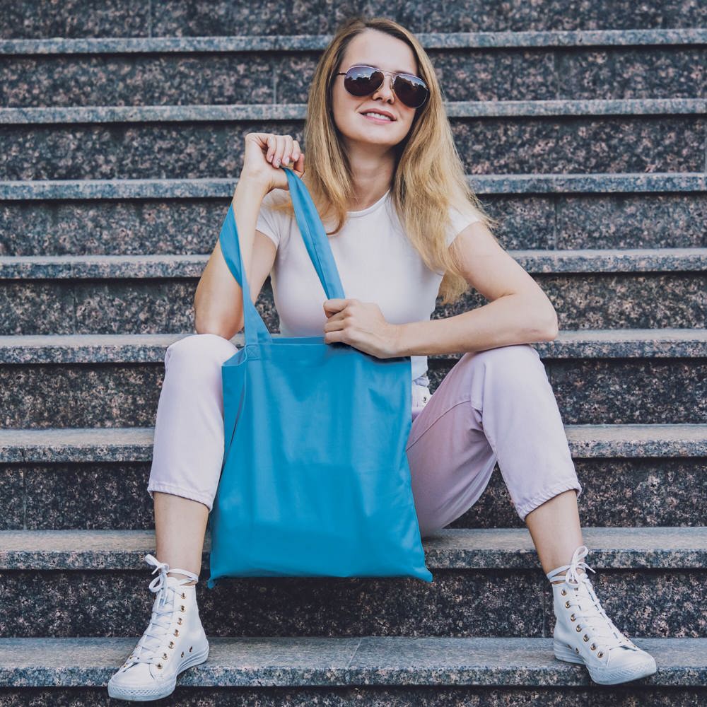 Young beautiful woman with linen eco bag on stairs background - Hidalgo