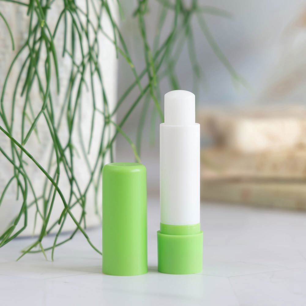 Opened lip balm stick on marble conutertop near potted green pla - Hidalgo