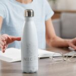 Woman taking thermo bottle indoors closeup view - Hidalgo